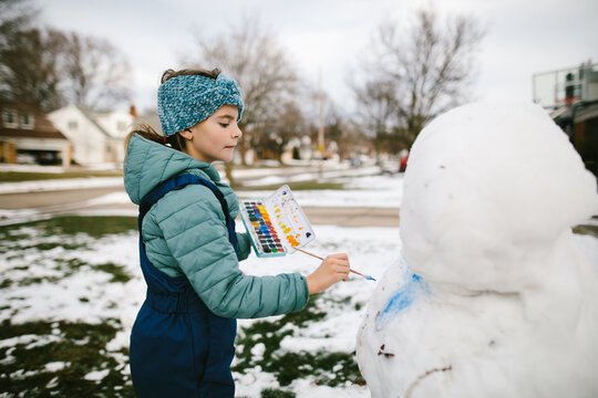 Girl uses paint to decorate snowman