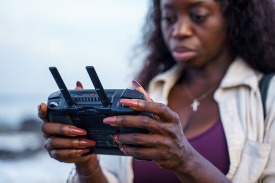 Woman holding a remote controller of a drone at the beach