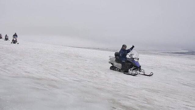 Group of tourists riding snowmobiles with a guide at Vatnajokull glacier in Iceland. Active sport, recreation, lifestyle.