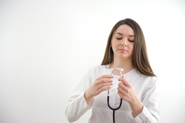 young beautiful doctor nurse anesthesiologist rheumatologist therapist pediatrician on a white background is preparing to examine the patient doctor touches a stethoscope