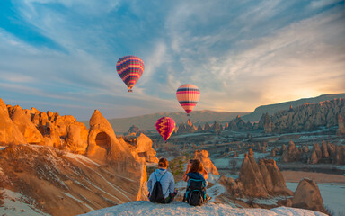 Fototapeta Hot air balloon flying over spectacular Cappadocia - Girls watching hot air balloon at the hill of Cappadocia obraz
