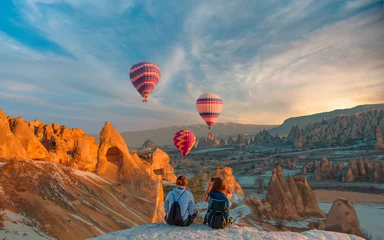 Deurstickers Hot air balloon flying over spectacular Cappadocia - Girls watching hot air balloon at the hill of Cappadocia © muratart