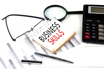 BUSINESS SKILLS text on notebook with calculator on diagram background