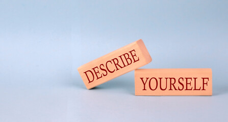 DESCRIBE YOURSELF text on the wooden block, blue background