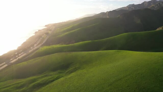 2023 - Excellent aerial footage of sunlight breaking on the green hillsides abutting the 101 Highway and coast on Gaviota, California.