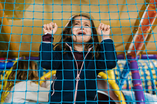 Girl crying behind net on playground