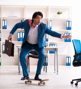 Young handsome businessman with longboard in the office