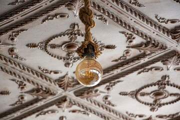 The vintage light bulb hanging on the ceiling of an old building. A Retro Edison light bulb hanging on the ceiling