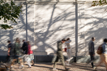 Walking people blurred in motion on sidewalk