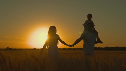 Fototapeta na wymiar Little daughter, father mother travel, play, enjoy nature outdoors, dream, sunset. Happy family of farmers with child walks through wheat field in sun. Slow motion. Mom, dad, kid are walking together