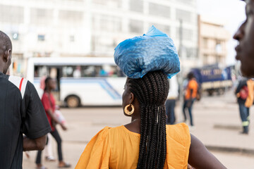 portrait of woman in african street with bag of peanuts on his head