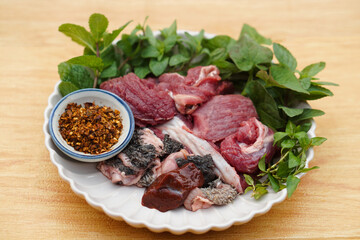 Fresh raw beef and Thai local herbal vegetables, prepare for cooking. Concept, food ingredient. Tradiotnal weird food. Popular menu in northern of Thailand.  Local food. Food ingredients to cook Larb.