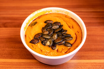 Hokkaido pumpkin soup with seeds, take away vegan food order on a wooden table