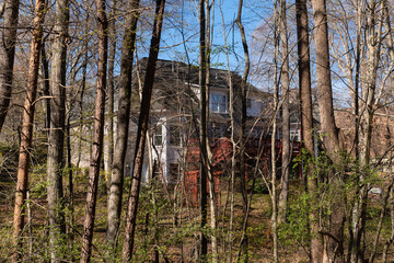 Large suburban house tucked into the woods, partially hidden from view. Real estate and home...