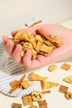Hand grabbing Chex mix snack from paper bag. 