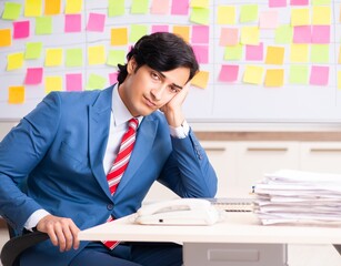 Young handsome employee with many conflicting priorities