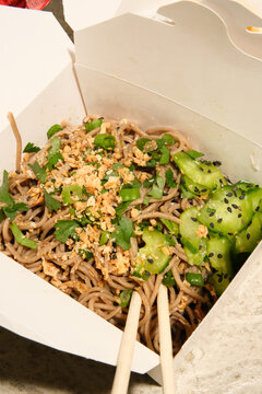 Soba noodle salad dish from food truck cart in to-go packaging. 