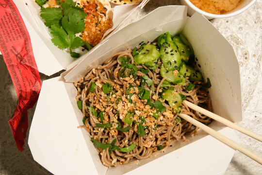 Soba noodle salad dish from food truck cart in to-go packaging. 