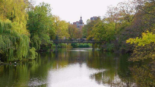 2022 - People cross a bridge in the public park Orstedsparken on an overcast day in Copenhagen, Denmark.