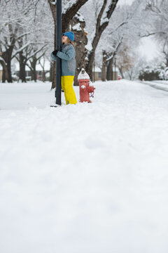 Boy playing in snow acting like his tongue is stuck to pole