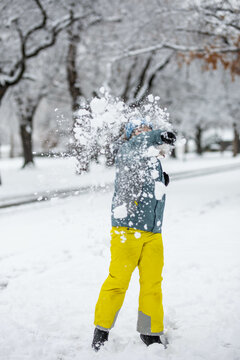 Boy throwing snowball at camera in neighborhood front yard