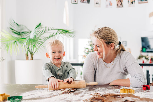 A child and his mother rolling out gingerbread cookie dough together