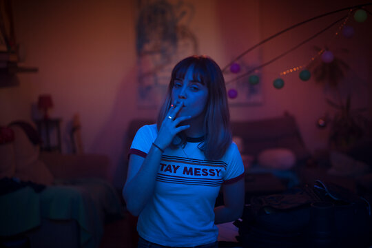 Cinematic neon light portrait of woman smoking at party
