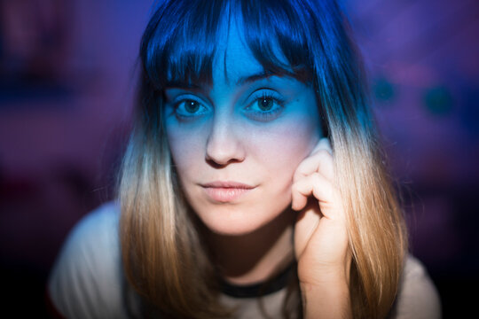 Young woman with blue neon light looking at camera