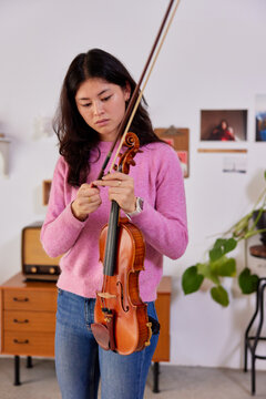 Young woman tightening violin bow