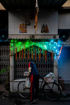 A bicycle newspaper delivery worker stops to pray at a shrine in India