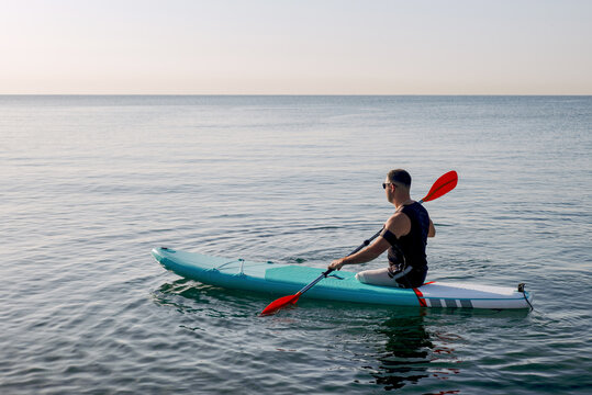 A man without legs floats on a Sup board in the early morning 