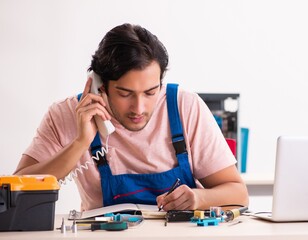 Young male contractor repairing computer