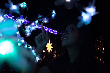 Woman amazed by the bright lights of a Christmas tree