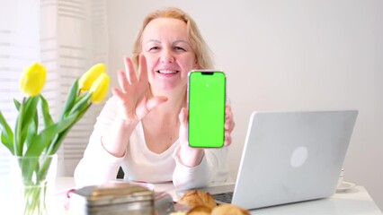 woman shows thumb up sends air kiss in her hands green screen chroma key phone recommends next to a laptop yellow tulips breakfast woman is very satisfied happy offers you an advertisement