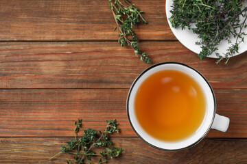 Aromatic herbal tea with thyme on wooden table, flat lay. Space for text