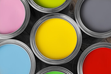 Cans of different paints on wooden table, flat lay
