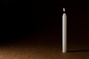 Burning church wax candle on dark background, space for text