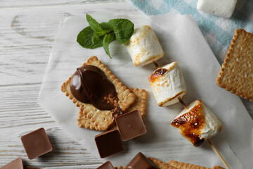 Ingredients for delicious sandwich with roasted marshmallows and chocolate on white wooden table, flat lay