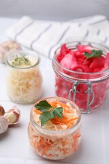 Delicious sauerkraut prepared according to different recipes on white table, closeup
