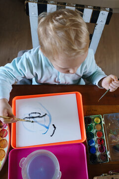 Little child painting with blue watercolors 