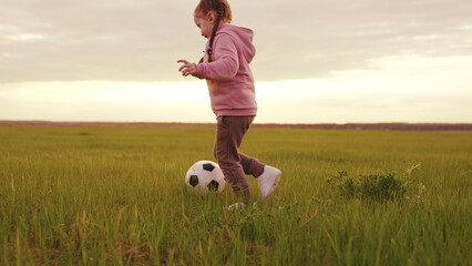 Child Duthe, plays football green field sunset. Little Child Kid kicking ball foot sunset. football...