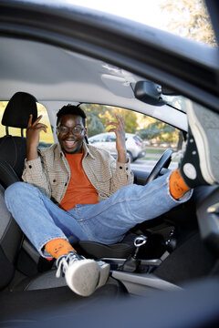 Portrait of carefree man lying and gesturing on front seat of the car