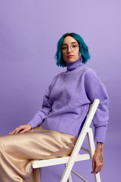 Stylish woman with blue hair sitting on chair