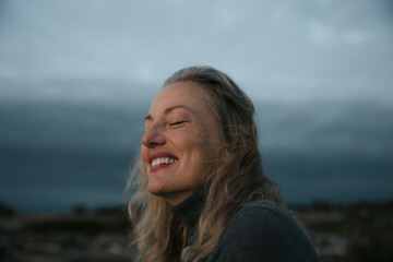 Mature woman feeling spiritual alone at sunset.