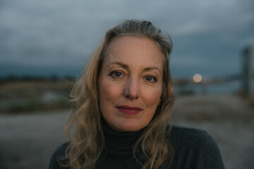 Healthy mature woman looking at the camera for sunset portrait.