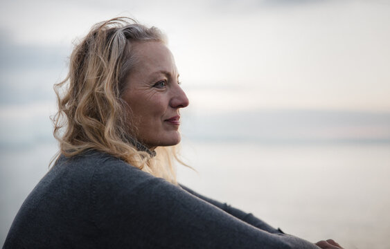 Thoughtful mature woman looking out at sunset.