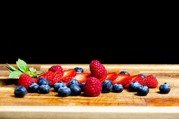 Sliced Strawberry with berries on a wooden table