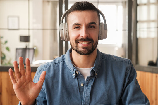 Smiling man looking at camera and waving hand 