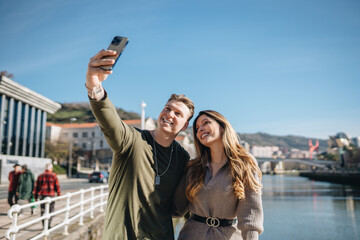 Happy couple taking selfie on smartphone in city