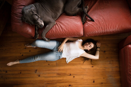 Relaxed woman with a dog lying on the floor of living room
